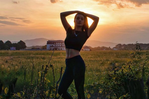 Person in a serene meditation pose at sunset, radiating peace.