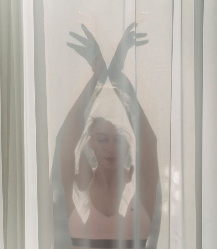 Woman gracefully performing a yoga pose on a mat, surrounded by soft light.